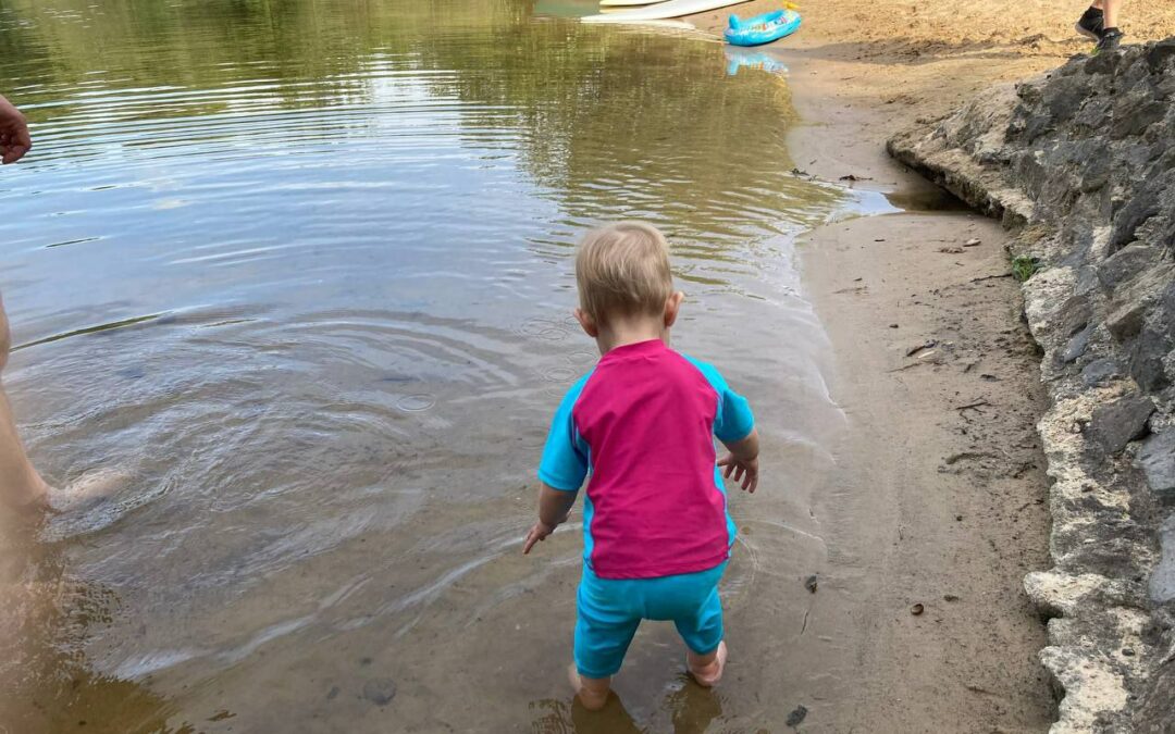 Kleinkind in der Urlaubszeit am Strand - von hinten fotografiert, um das Gesicht nicht zu zeigen